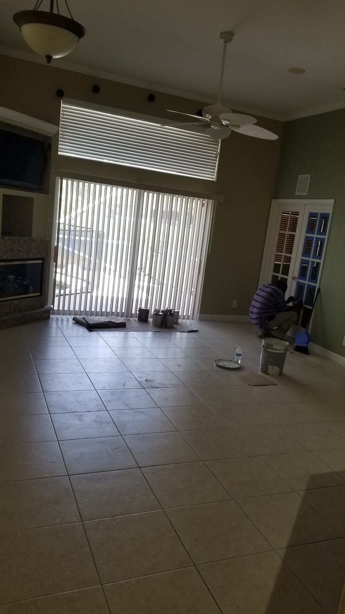 Spacious living room with large sliding doors, a fireplace, and a person painting a door.