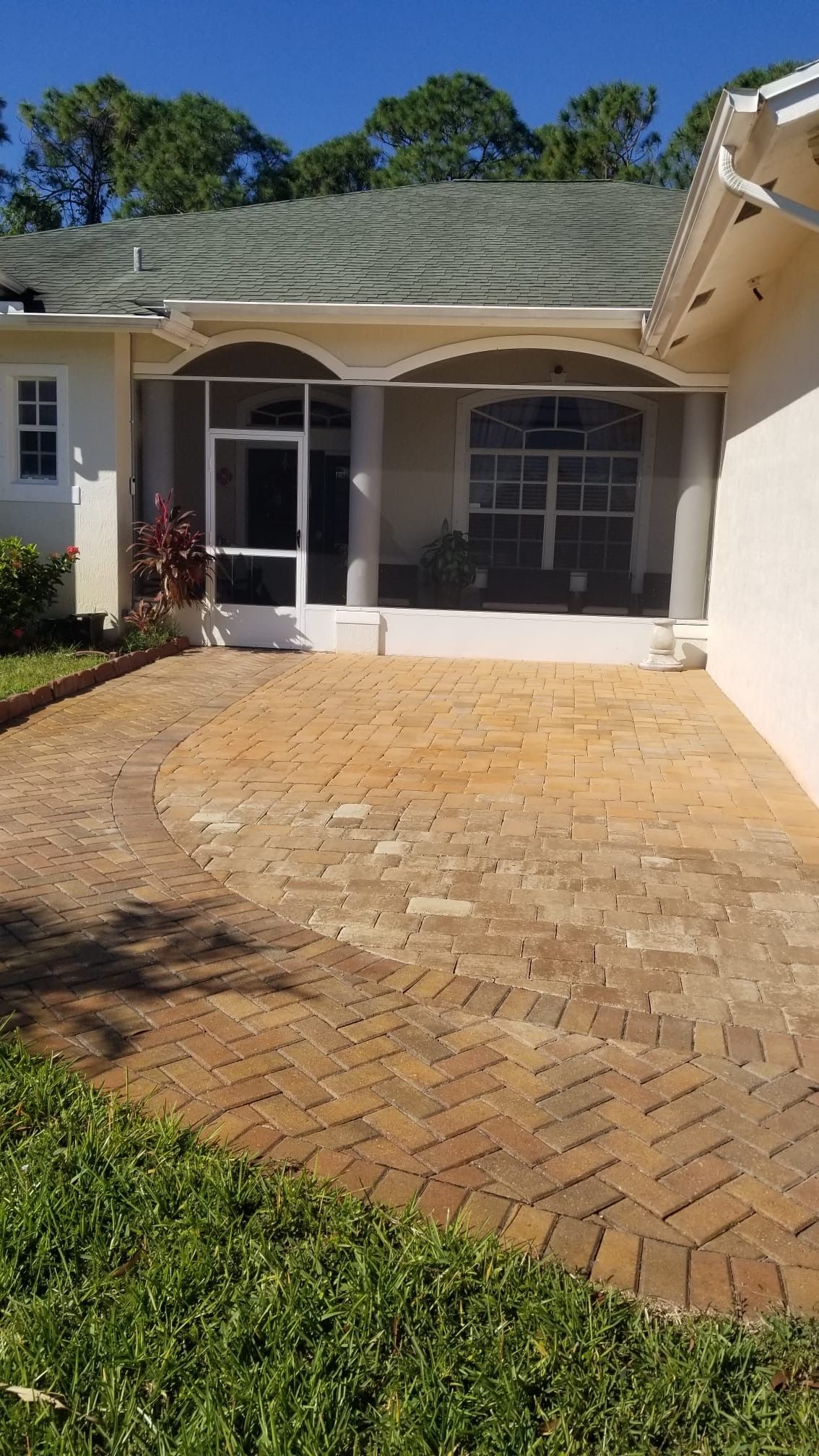 Brick patio leading to a screened porch with a white trim and arched entry.