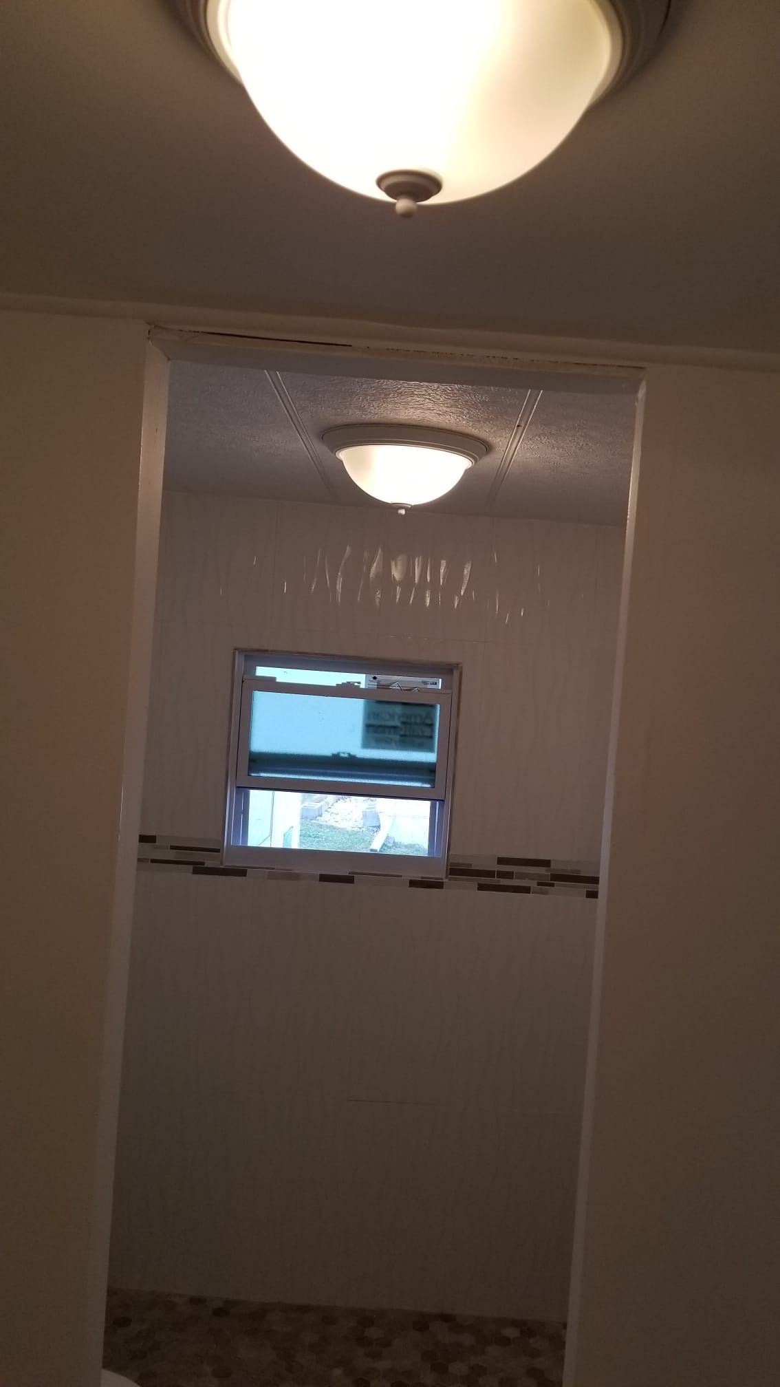 Bathroom interior with two ceiling lights, a small window, and tile accents.
